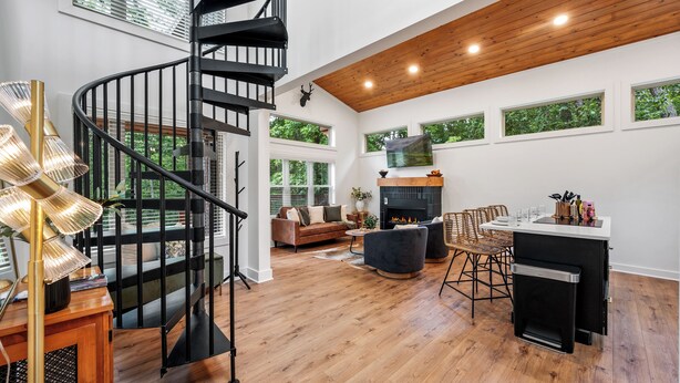 A modern living room with a spiral staircase, a fireplace, and large windows. - Under 1 mile to Dollywd, 5 mins Pkwy - 2 Kings/2 BA - Small fam or couples (Pigeon Forge)