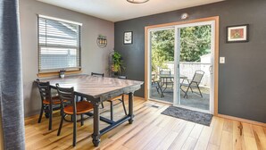 A dining area with a wooden table and chairs, a window with blinds, a potted plant, and a sliding glass door leading to an outdoor patio. - Teak and Jordan Estates- Sleeps 28! (Albany)