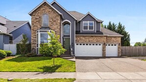 A two-story house with a stone facade, a front garage, and a well-maintained lawn. - Teak and Jordan Estates- Sleeps 28! (Albany)