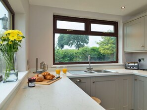 A kitchen with a large window, a sink, a toaster, and a vase with flowers.
