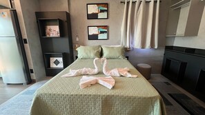 Een hotelkamer met een bed, een klein nachtkastje, een bank, een open haard en kunst aan de wanden.