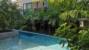 Un edificio moderno con piscina rodeada de exuberante vegetación.