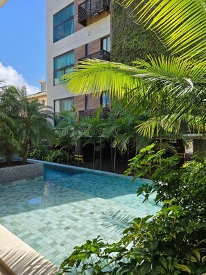 Un edificio moderno con piscina rodeada de exuberante vegetación.