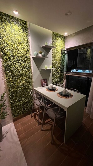 Una cocina moderna con una pared cubierta de follaje verde, una pequeña isla con taburetes altos y un horno empotrado.