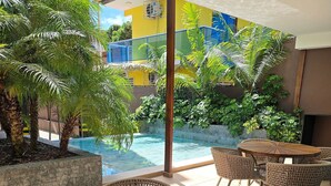 Zona de piscina con mobiliario de mimbre y vistas a la piscina y zonas verdes.
