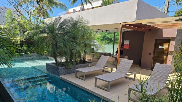 Un área de piscina con sillones de descanso y una pérgola.