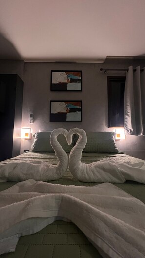 Una habitación de hotel con una cama, dos cuadros en la pared y una decoración de toallas con forma de corazón.