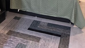Habitación de hotel impecable con cama, televisor de pantalla plana, calefacción integrada y estante.