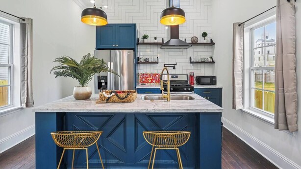 A modern kitchen with a central island, blue cabinets, and pendant lighting.
