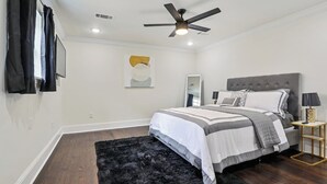 A bedroom with a bed, a ceiling fan, a black rug, and a nightstand.
