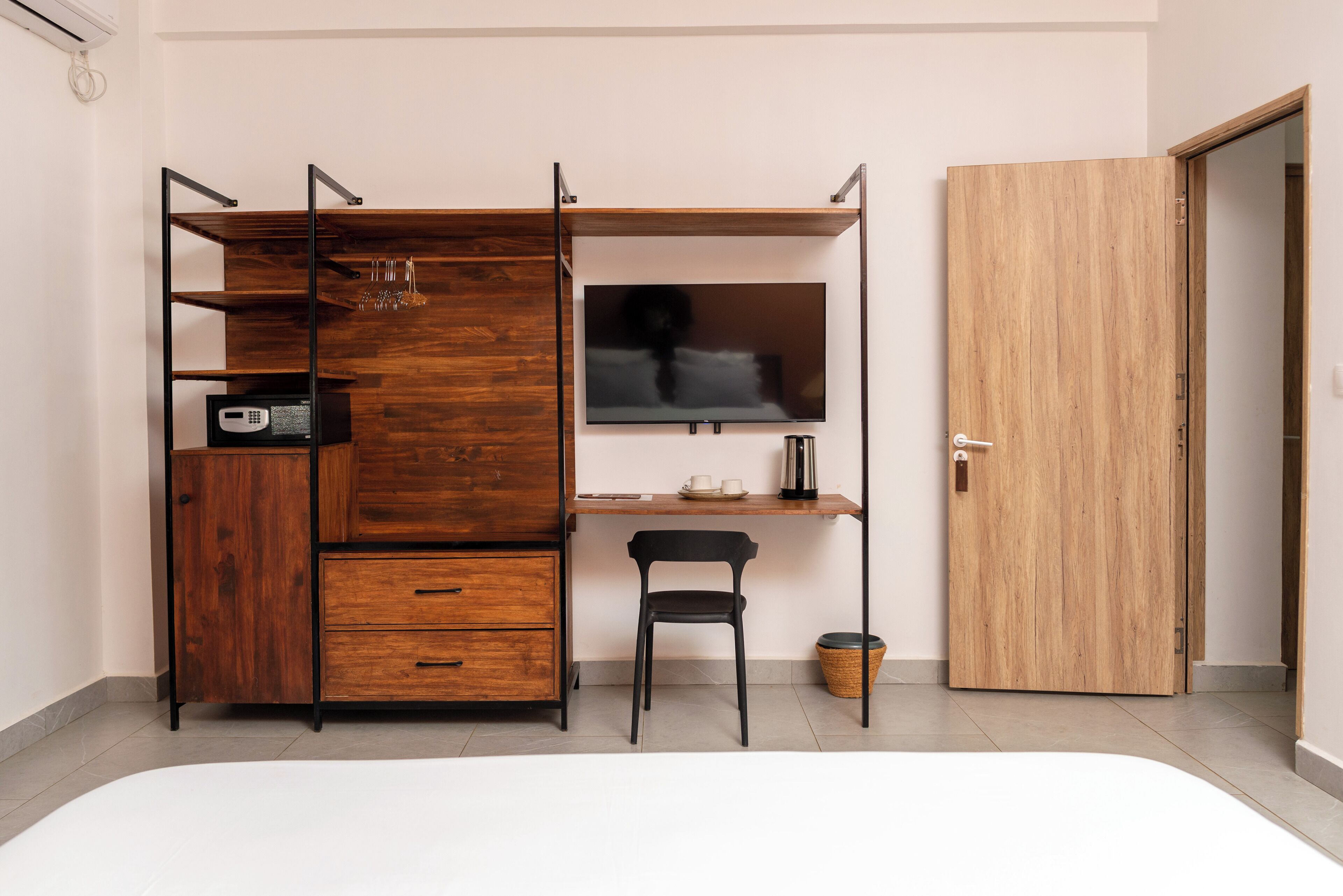 Une pièce de taille modeste, comprenant une armoire en bois, un bureau, une chaise et un téléviseur.