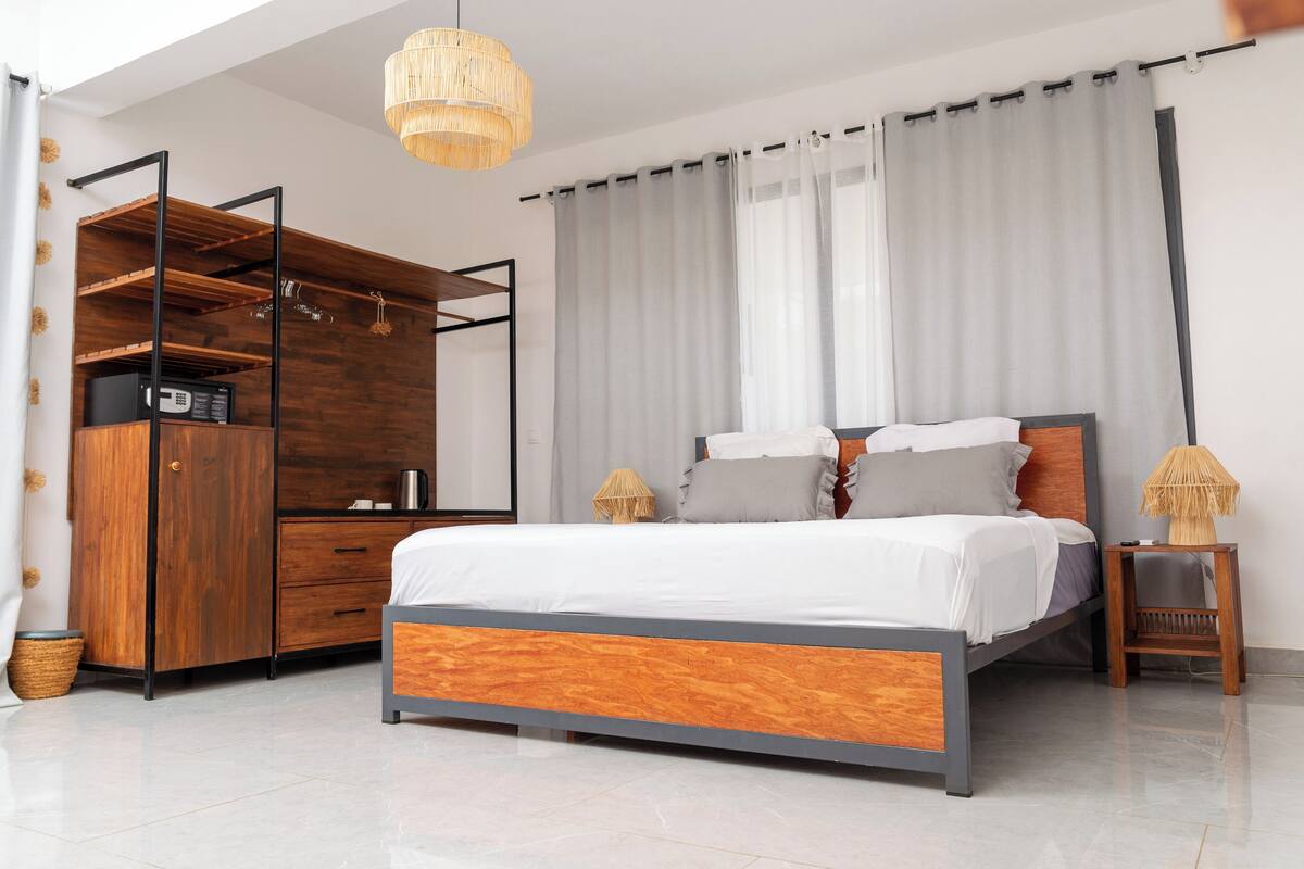 Une chambre à coucher moderne avec un lit, une armoire en bois et un luminaire suspendu.