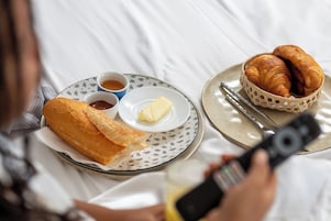 A breakfast setting with croissants, butter, and tea on a plate.