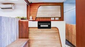 A reception desk with a 'TOWNHOUSE' sign, a wooden panel wall, a white reception counter, and a bench. - Townhouse Zero Mile Gandhi Setu (Patna)