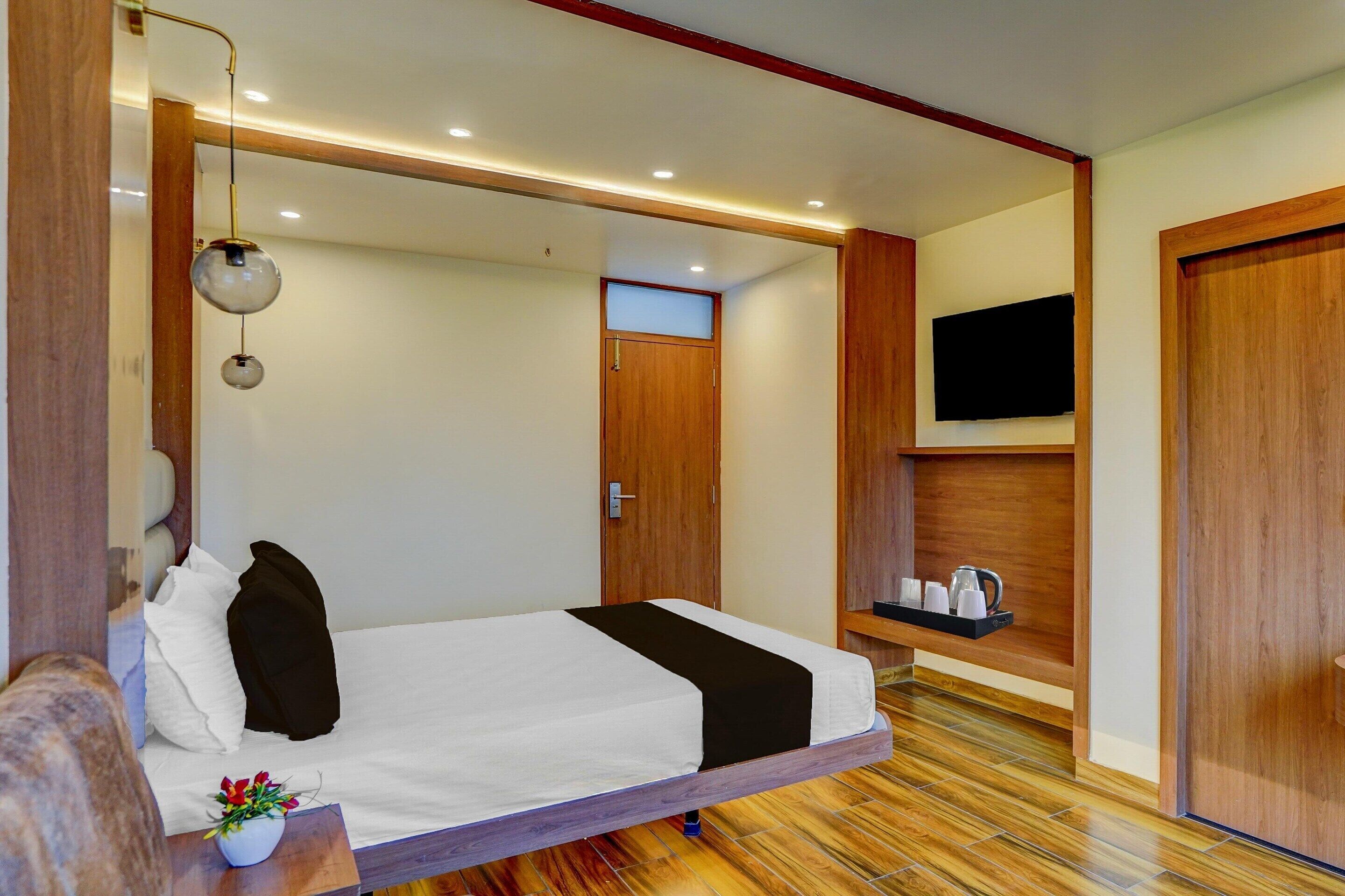 Une chambre à coucher avec un lit, une table de chevet, une télévision et un plancher en bois.
