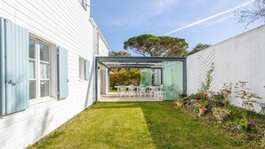 A house with a glass-enclosed patio, white siding, and a small garden.