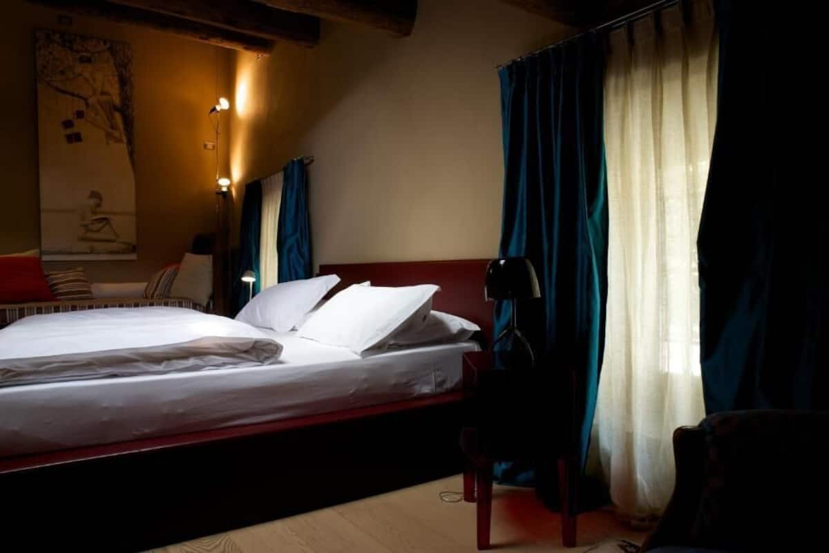 A hotel room with a bed, a chair, a lamp, and curtains.