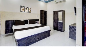 A modern hotel room with a large bed, a wardrobe, a vanity, and a ceiling with a blue pattern. - Hotel Tanwar (Jaipur)