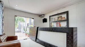 A modern lobby with a reception desk, leather sofas, a tiled floor, and a wall-mounted TV. - Hotel Tanwar (Jaipur)