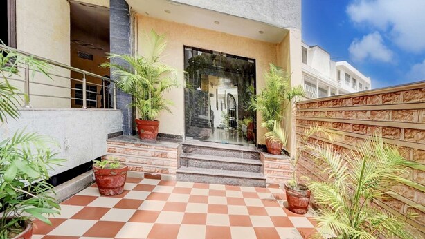A building entrance with a checkered floor, potted plants, and a staircase leading to the door. - Hotel Tanwar (Jaipur)