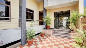 A hotel entrance with a checkered floor, potted plants, and a staircase leading to the entrance. - Hotel Tanwar (Jaipur)