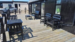 A wooden deck with outdoor seating and a car parked nearby.