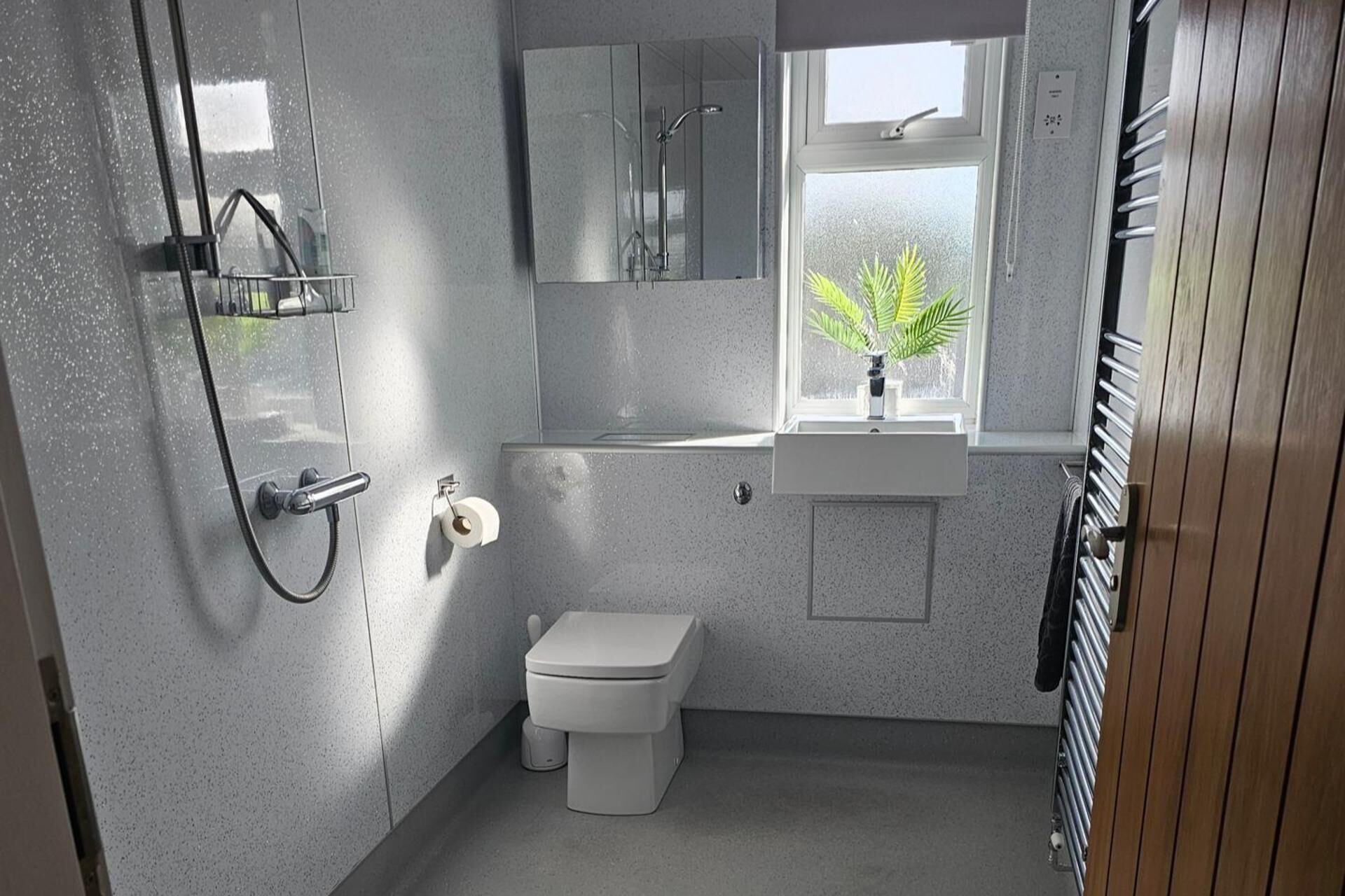 Une petite salle de bain comprenant des toilettes, un lavabo, un miroir et une douche.
