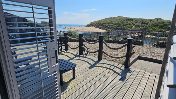A wooden deck with a view of a beach and hills. - 2 Bed Cottage-sleeps 4-harbour & Sea View (Peterhead)