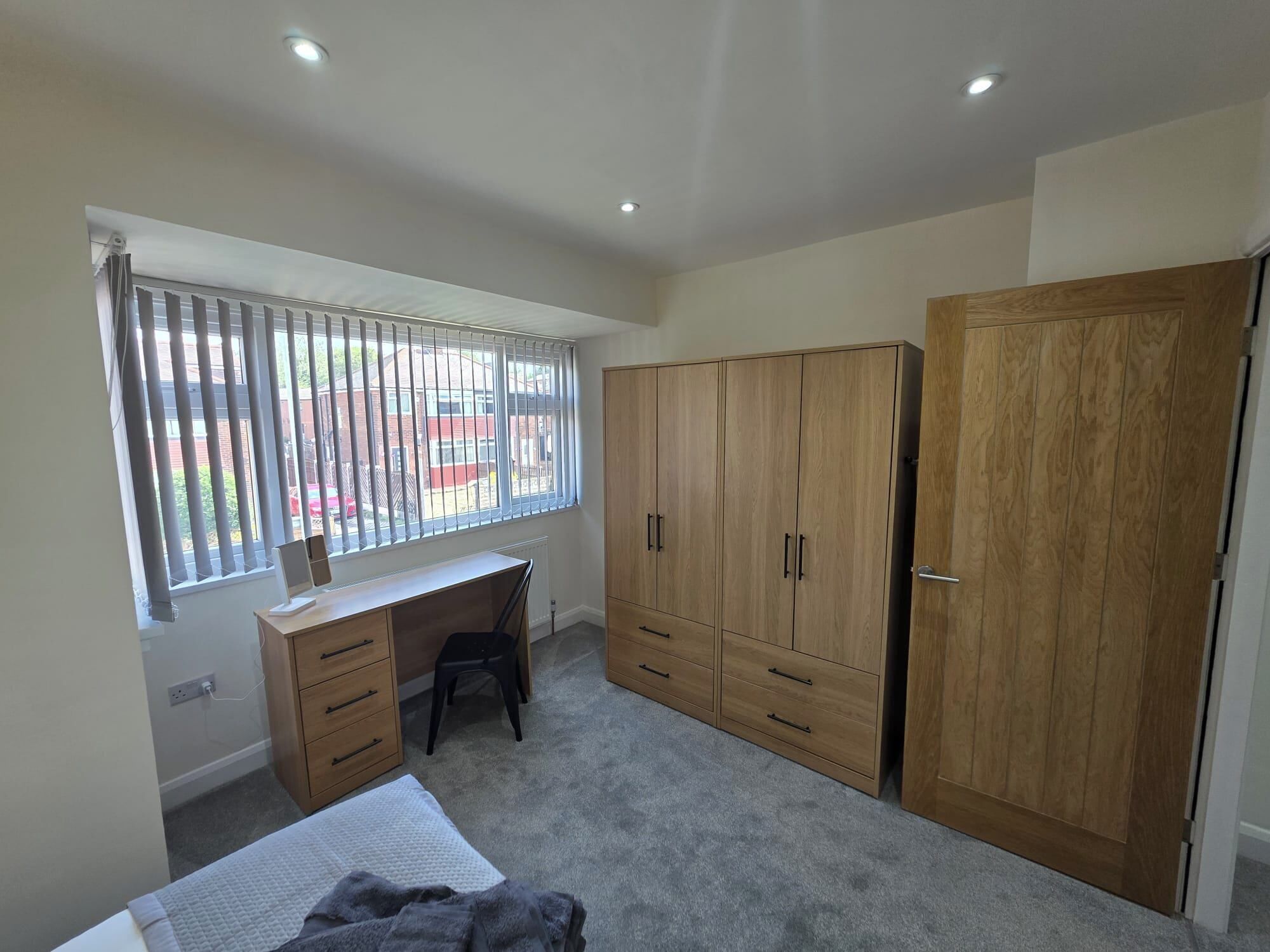 A bedroom with a bed, a desk, a chair, and a wardrobe.