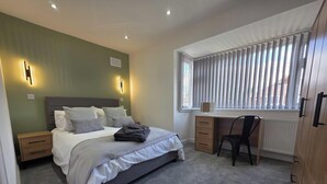 A bedroom with a bed, bedside tables, a desk, and a chair. - House - Sleeps 4 - Parking - Garden - City Centre (Leeds)