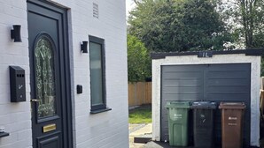 A house with a black door, a garage door, and two trash bins labeled 'Leeds Recycling for Leeds'. - House - Sleeps 4 - Parking - Garden - City Centre (Leeds)