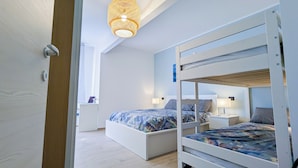 Une chambre moderne avec des lits superposés, une table de chevet avec une lampe et une fenêtre avec des rideaux.