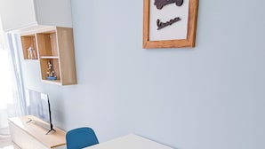 Une pièce moderne avec une table blanche, des chaises bleues, un meuble en bois et un tableau encadré au mur.