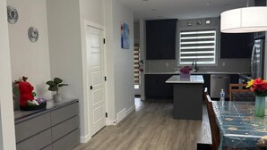 Une cuisine moderne avec un coin repas, un plancher en bois et une vue sur le salon.