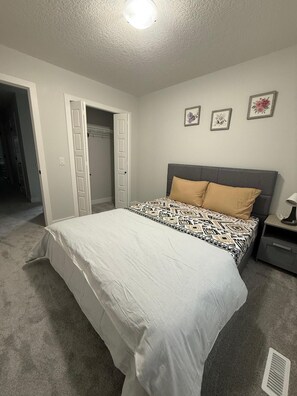 A bedroom with a bed, a nightstand, a closet, and a ceiling light. - Detached house in Hotchkiss SE (Calgary)