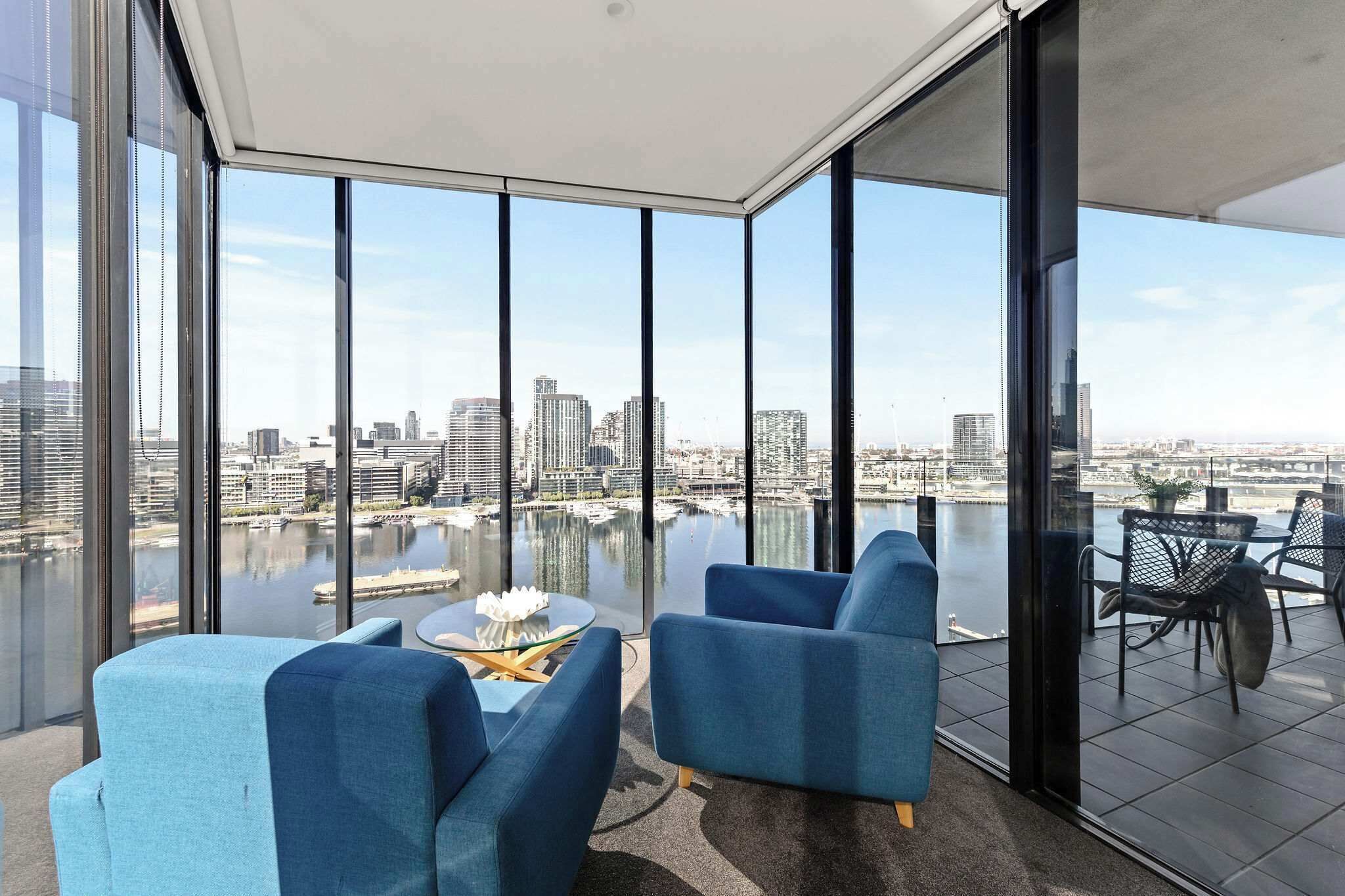 A modern balcony with a city view, large windows, and blue seating.