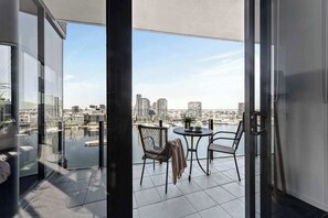A balcony with a city view, a table with chairs, and a potted plant.