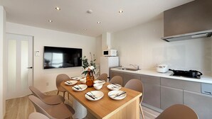 A modern kitchen with a dining area, equipped with a microwave, stove, and sink. - Wanoyado Kanayama (Hiroshima)