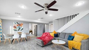 A modern living room with a grey sofa, a red throw blanket, and a ceiling fan. - This house is a 5 bedroom(s), 3 bathrooms, located in Phoenix, AZ. (Phoenix)