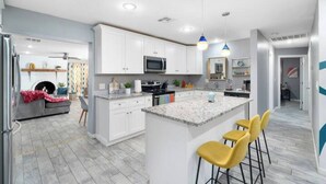 A modern kitchen with white cabinets, a granite countertop, and a central island with bar stools. - This house is a 5 bedroom(s), 3 bathrooms, located in Phoenix, AZ. (Phoenix)