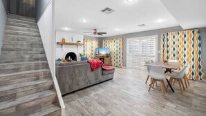 A modern living room with a grey sofa, a dining table with chairs, and a staircase. - This house is a 5 bedroom(s), 3 bathrooms, located in Phoenix, AZ. (Phoenix)