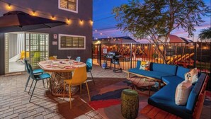 Eine Außenpatio-Terrasse mit rundem Tisch, Stühlen, einer Couch und einem Grill.