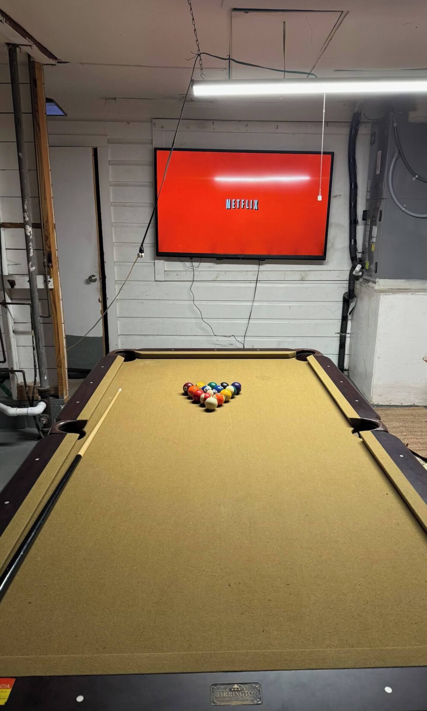 Una mesa de billar con un televisor rojo montado en la pared superior.