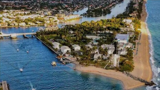 An aerial view of a coastal property with a beach, a marina, and residential buildings.