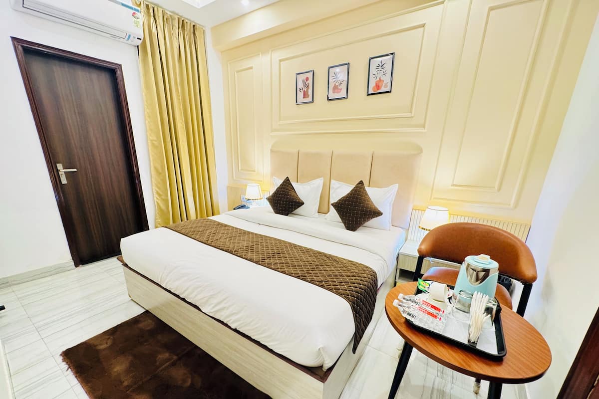 Habitación de hotel con una cama, una mesita de noche con lámpara, una silla y una bandeja con artículos de aseo.