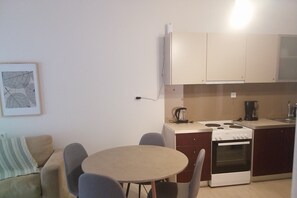 A compact kitchen with a stove, coffee maker, and a small dining table with chairs.