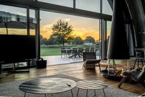 A modern living room with a large glass door leading to an outdoor patio, a fireplace, and a remote control on a table.