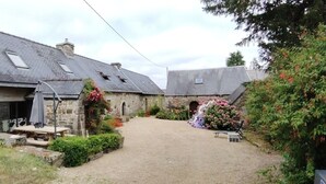 A stone building with a sloped roof, a small garden with flowers, and a gravel path leading to the entrance. - Breton house in the heart of the Monts d'Arrée   (Scrignac)