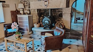 A cozy living room with a stone fireplace, a wooden ceiling, and a tiled floor. - Breton house in the heart of the Monts d'Arrée   (Scrignac)