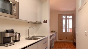 Una cocina moderna con microondas, cafetera y pileta de acero inoxidable.